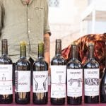 Tipos de vino. Colección de vinos Devotio en una mesa al aire libre en el Alto Túria, con botellas de variedades como Equites, Terra y Salvaxe, rodeadas de naturaleza y detalles artesanales